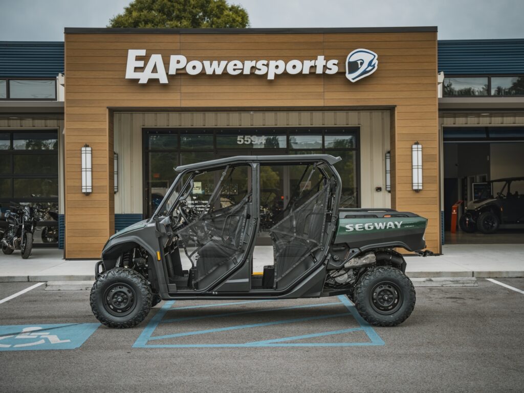 Green Segway ATV with open doors parked in a handicap space outside EA Powersports store building.