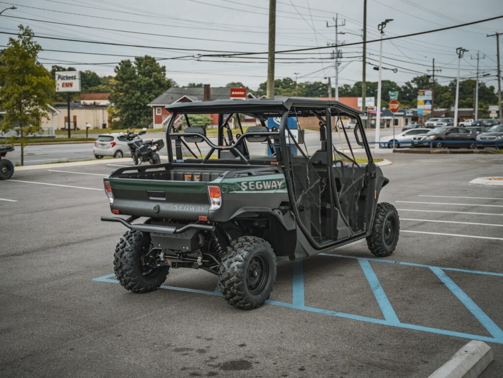 Green Segway off-road utility vehicle with a roll cage and four large tires parked in a blue-striped handicapped space
