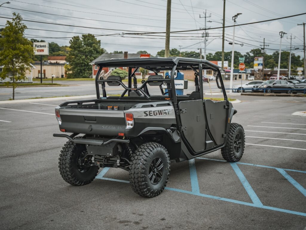 Dark gray Segway off-road utility vehicle with an open roll-cage, parked in a paved lot.