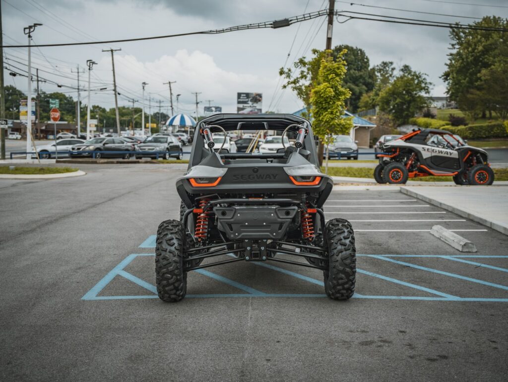 Rear view of a black Segway off-road UTV with red suspension in a parking lot.
